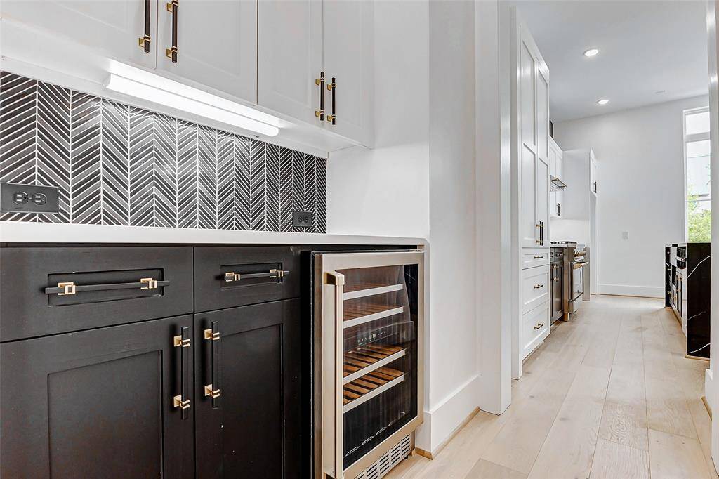 Tucked just off the kitchen, a stylish cocktail area offers the perfect spot for entertaining. With sleek cabinetry and thoughtful design, this space is ideal for crafting drinks, displaying glassware, or serving guests with ease.