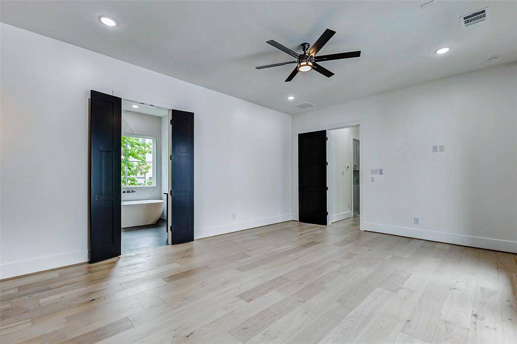 Enter the sophisticated primary bedroom, where sleek black French doors lead you into a luxurious ensuite bathroom.