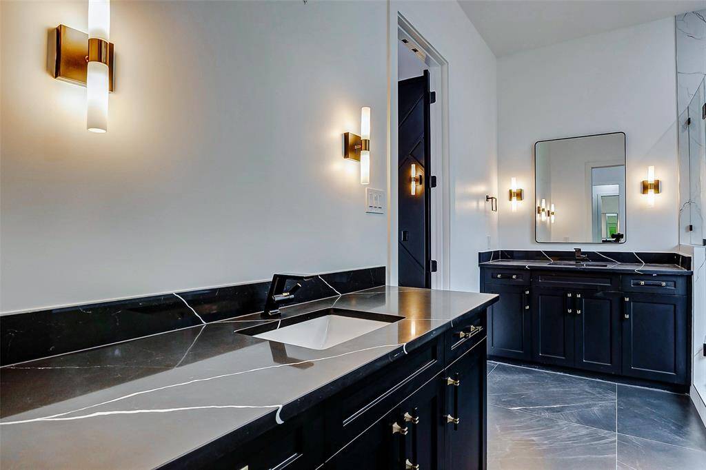 This elegant space features separate sinks with stunning black marble countertops, paired with chic black shaker cabinets for a sleek, modern look.