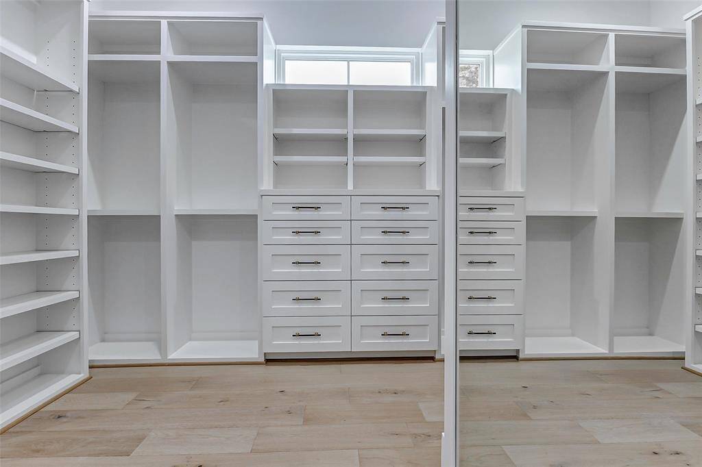 The spacious walk-in closet offers the ultimate in organization and style, featuring floor-to-ceiling built-ins and custom drawers.