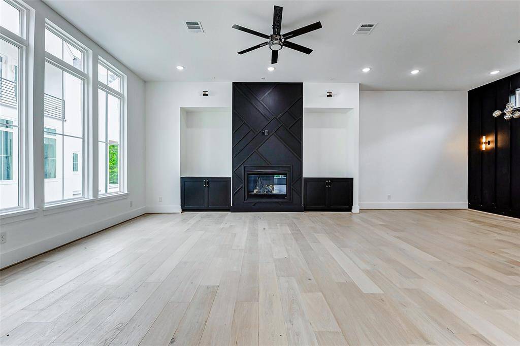 A modern fireplace adds warmth and sophistication, creating the perfect space for relaxation and entertaining. The expansive windows and soaring ceilings flood the room with natural light, while the engineered hardwood floors enhance the open, airy feel.