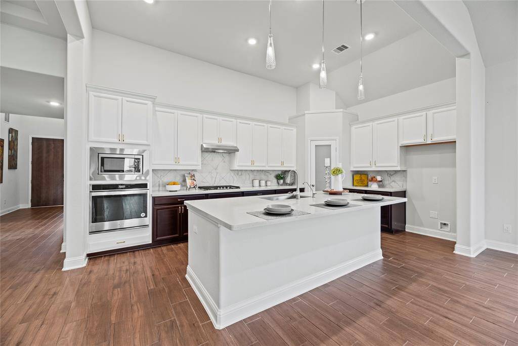 Gorgeous island kitchen boasts stainless steel appliances, gas cooktop, pendant lighting and a large corner pantry.