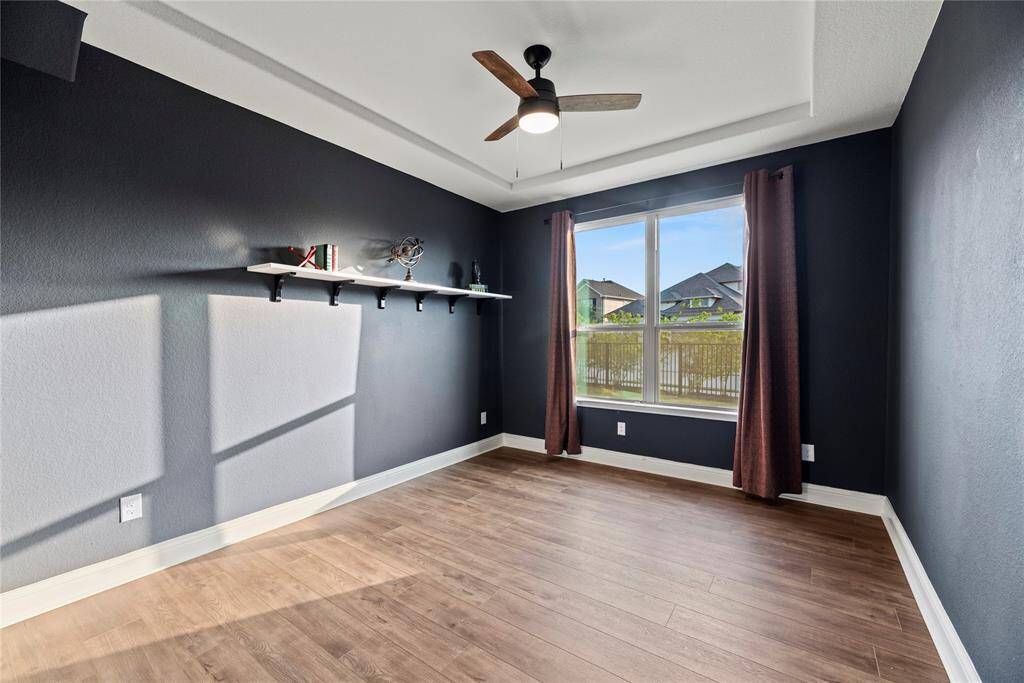 Private home office with wood-look tile flooring, tray ceiling and ceiling fan. Perfect for the remote professional.