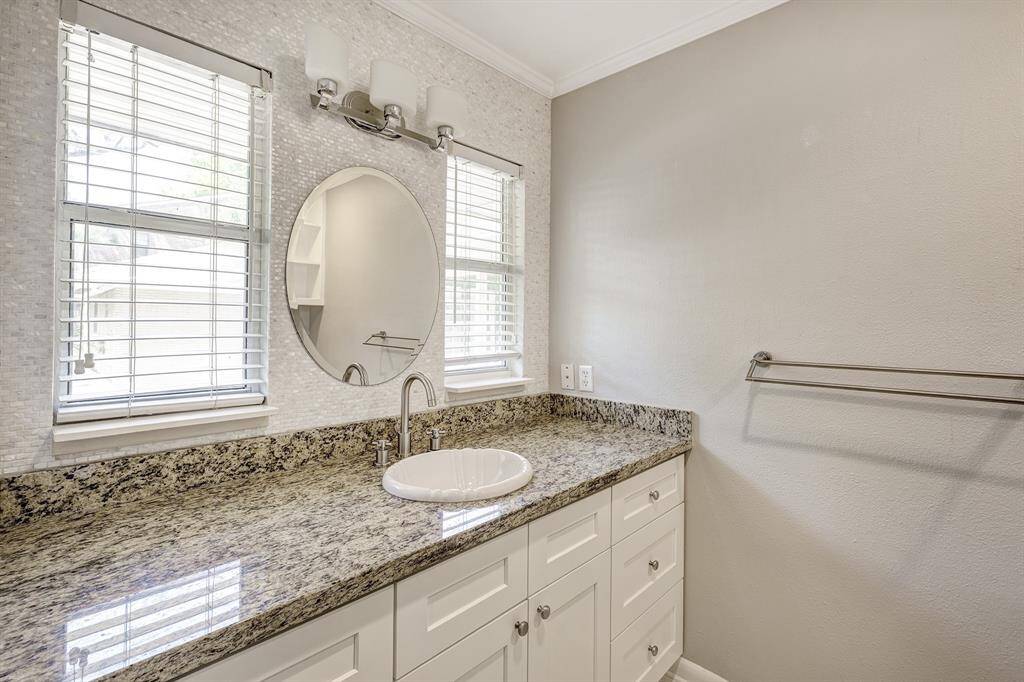 The primary bath has neutral colors, granite counter, and great light & views the back yard.