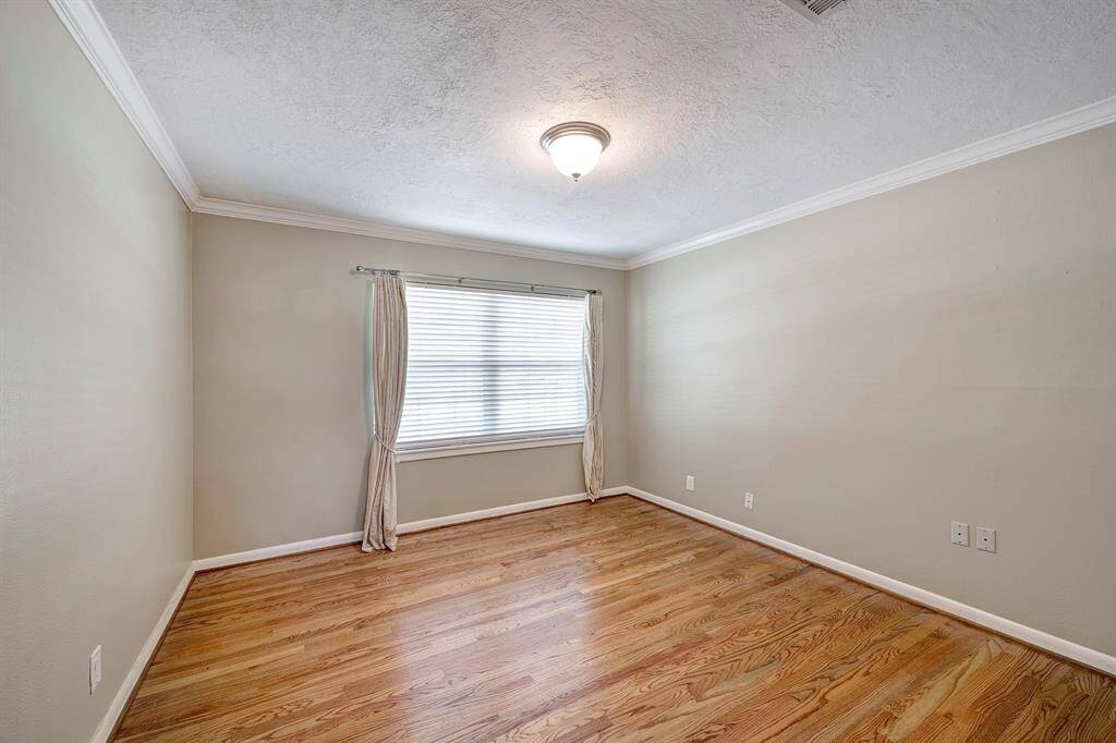 Another secondary bedroom with hardwood floors and neutral paint.
