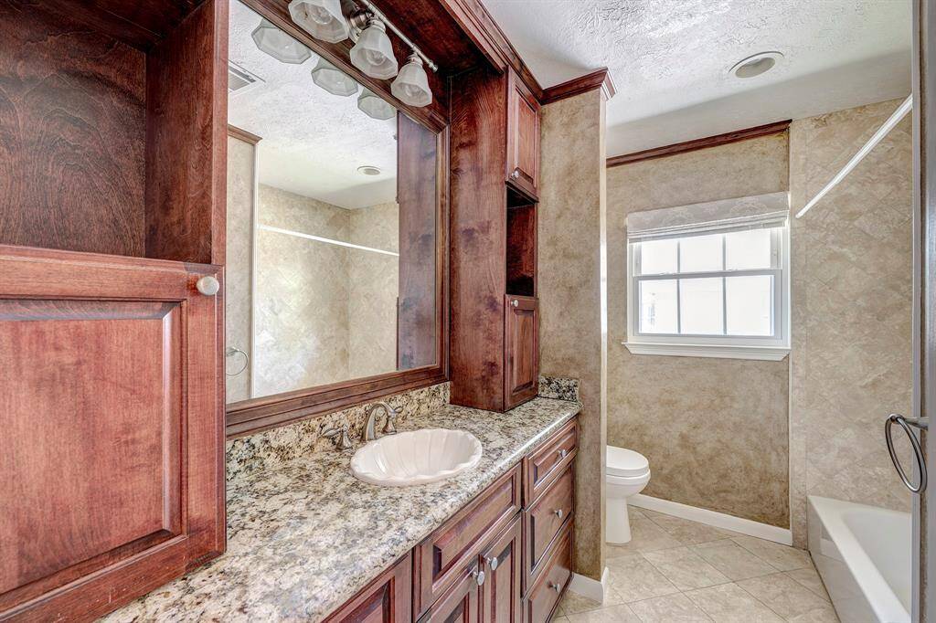 The secondary bath has been updated with wood cabinets, marble counters, bath and custom painted wals.