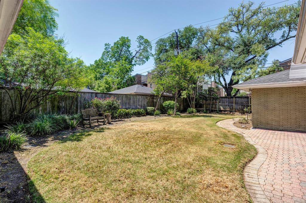 The beautiful, spacious back yard. Pretty brick patio & walkway around the back side of the garage to the right.