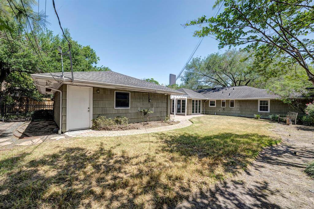 A view of the home from the back. There is a lovely wrought iron fence seperating the driveway from the yard. There is also a convenient door to the garage from the yard.