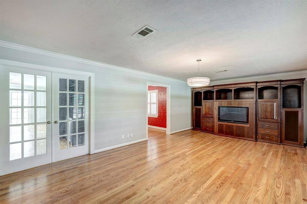 There are french doors leading to the den off of the kitchen. The formal dining room is seen to the side in red. Hardwood floors throughout the home.