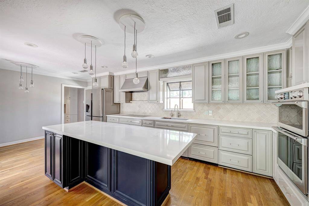The updated kitchen has double ovens, wood floors. an island with barstool/counter area, great storage and breakfast area . The utility room is through the open door.