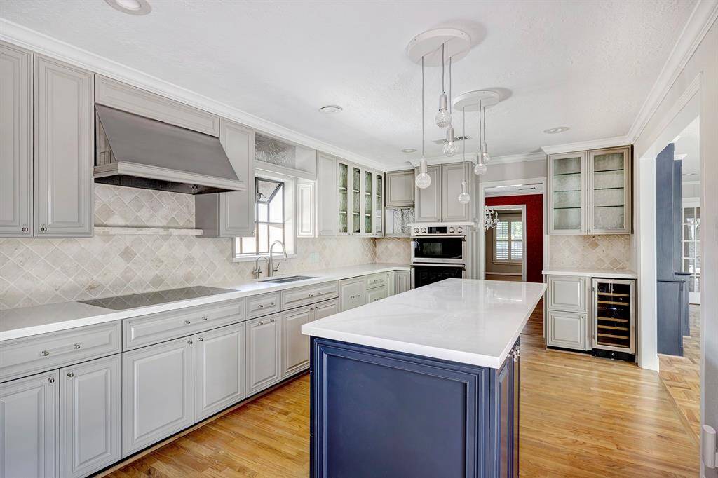 The kitchen has a dry bar with a wine fridge. It is open to the den.