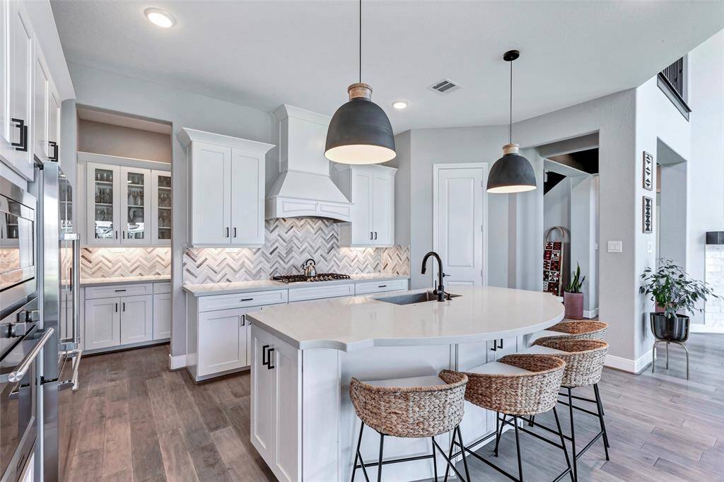 Kitchen island with custom edging and cabinets on four sides. Notice the butlers pantry with glass incerts