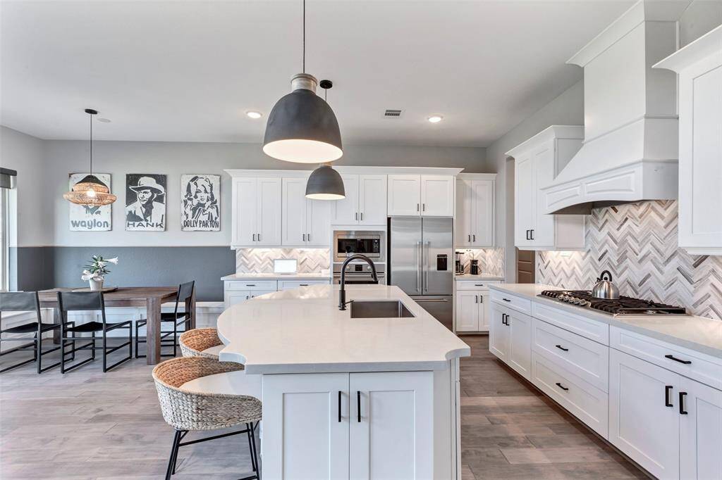 Herringbone backsplash with custom range hood and five burner gas cooktop