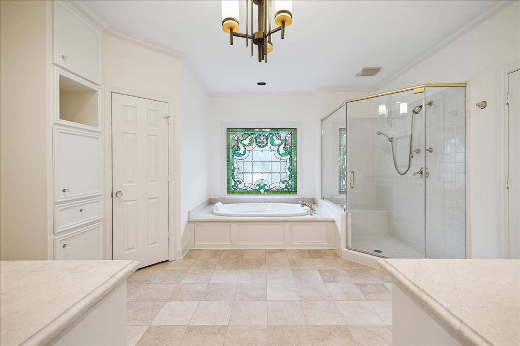 Neutral finishes, large tub and glass enclosed shower in primary bath 1.