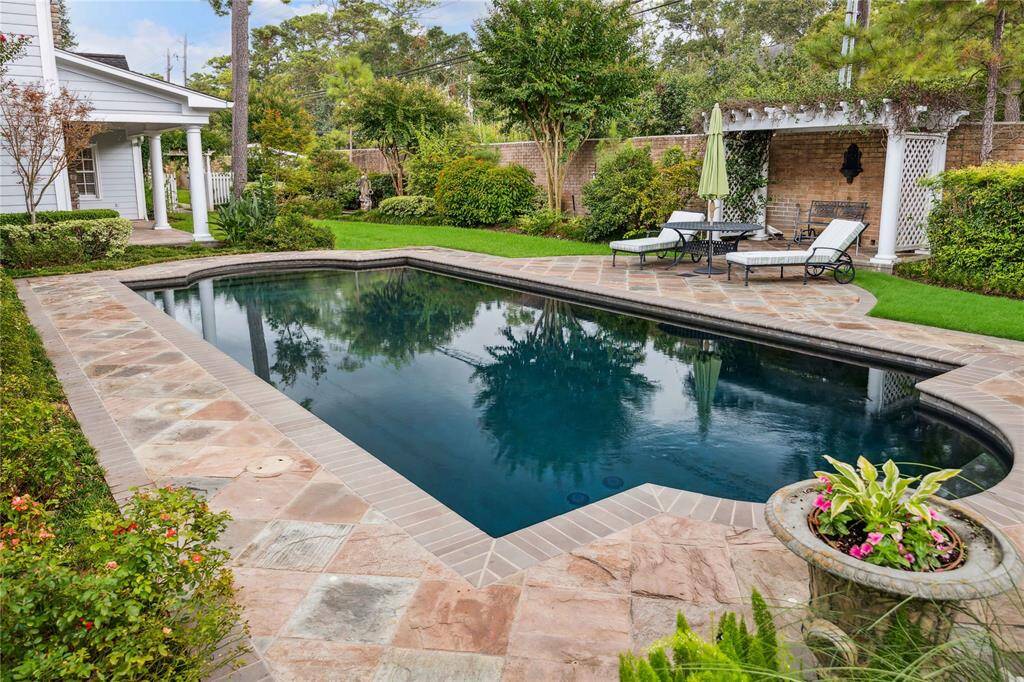 Poolside patio and pergola surrounded with lush landscaping.