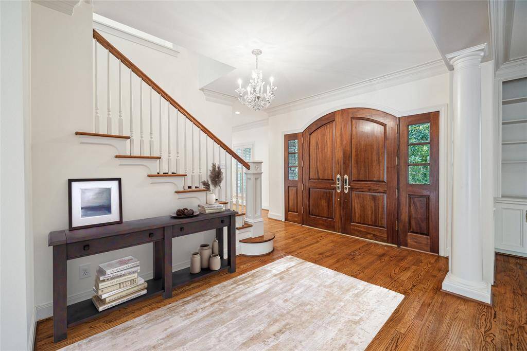 Entry with double doors, wood flooring and beautiful millwork opens to the dining and living rooms. (virtually staged)