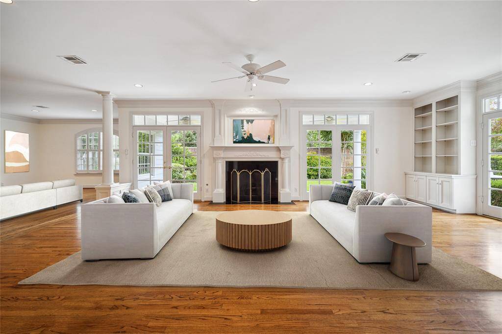 The living room is anchored with a lovely fireplace and French doors with transoms. (virtually staged)