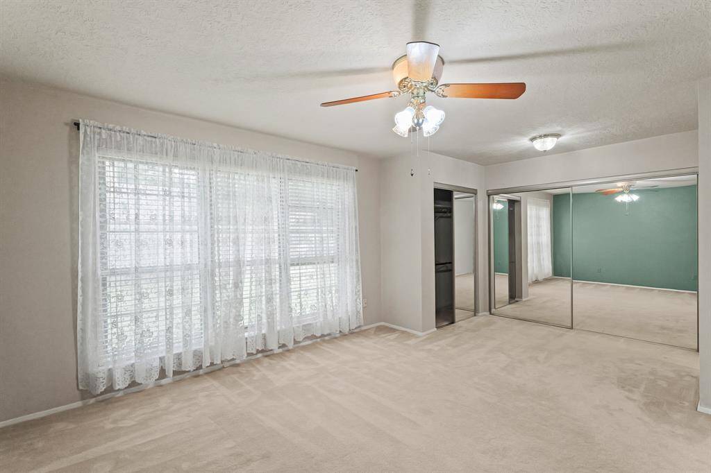 Primary Bedroom. Spacious primary bedroom with mirrored closets and a ceiling fan.