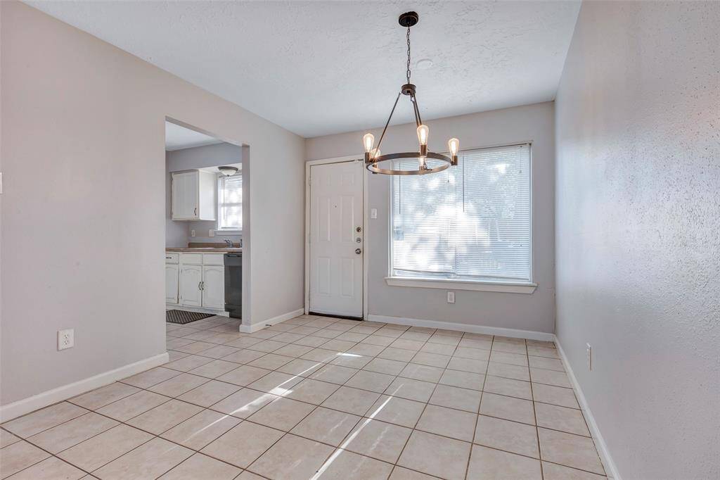 This inviting space serves as the dining area, with an open doorway leading to the kitchen and a closed door providing access to the backyard.