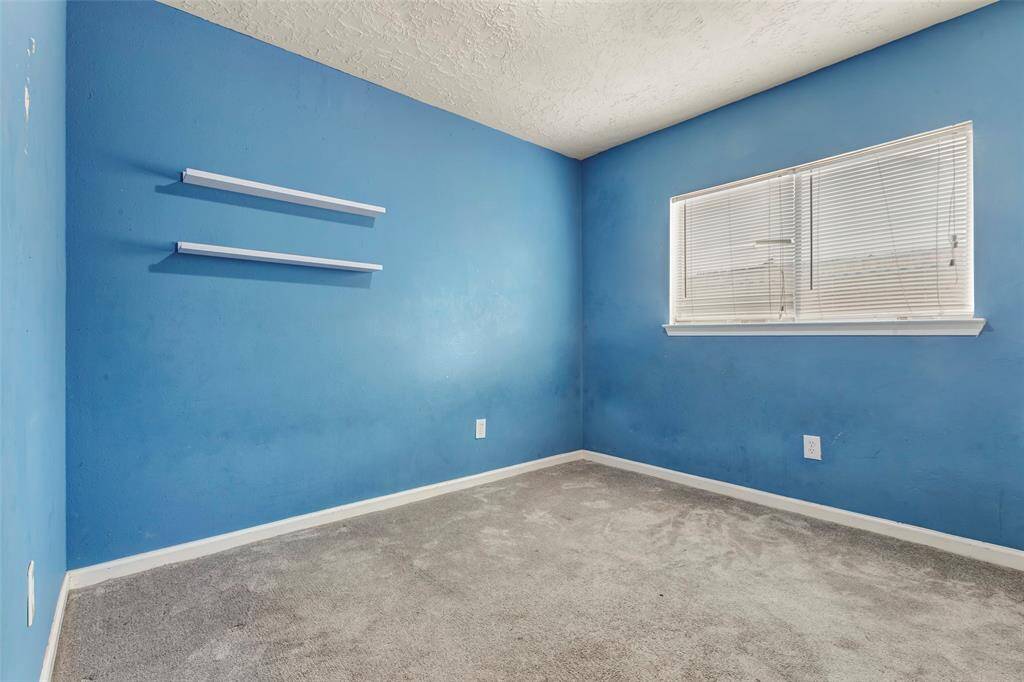 This bright secondary bedroom, features a cozy carpeted floor and a large glass window that fills the space with natural light.