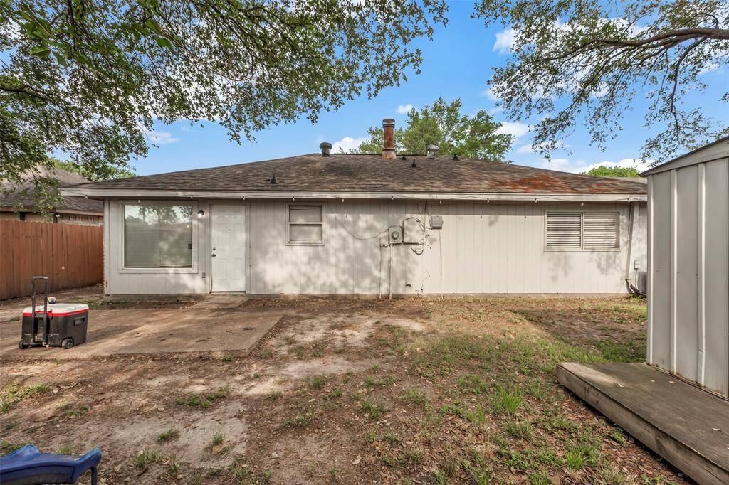 This back view of the home reveals an open patio—an ideal spot to set up your grill and enjoy alfresco dining. Surrounded by mature trees, the space offers natural shade and a tranquil setting for outdoor gatherings.
