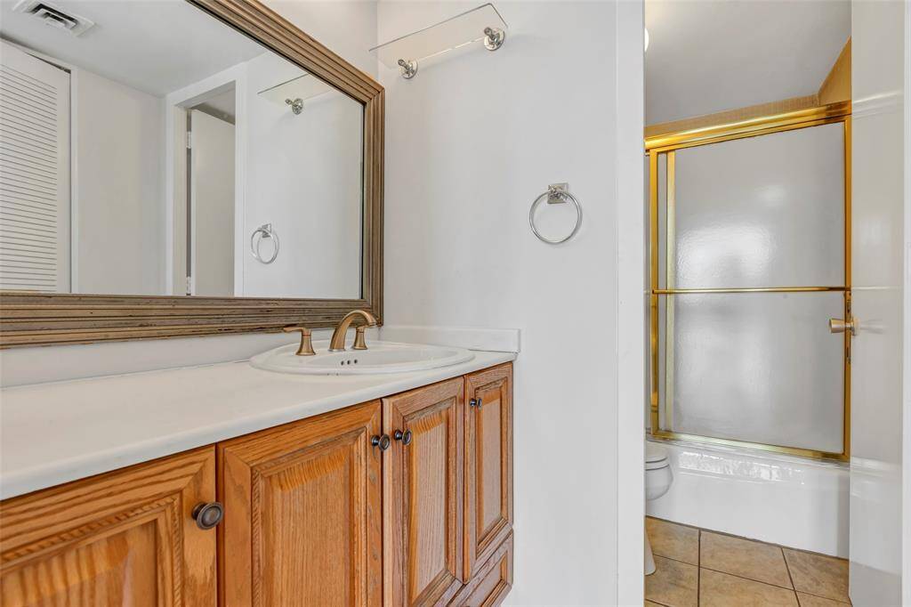 The secondary bedroom features an en-suite bath with a tub and shower combo, showcasing a stylish and modern finish.