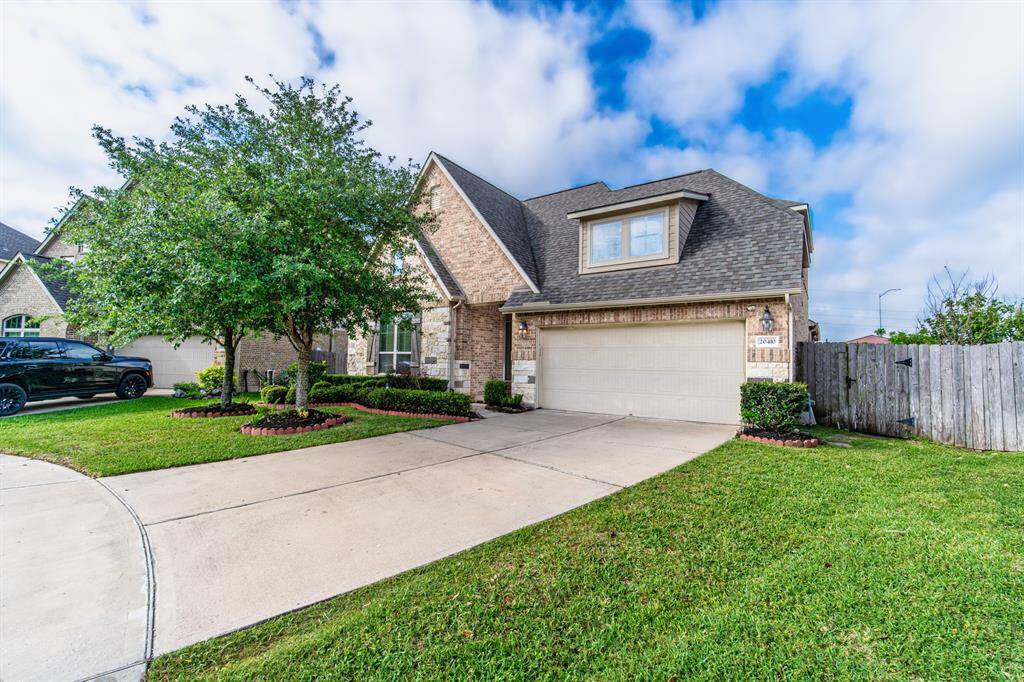 An inviting front yard with a spacious driveway, an appealing front porch, and trees for privacy.