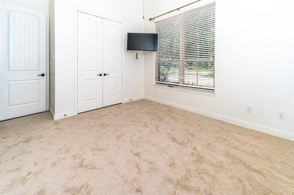 Bedroom with a TV and ensuite bath offers a view of the front.