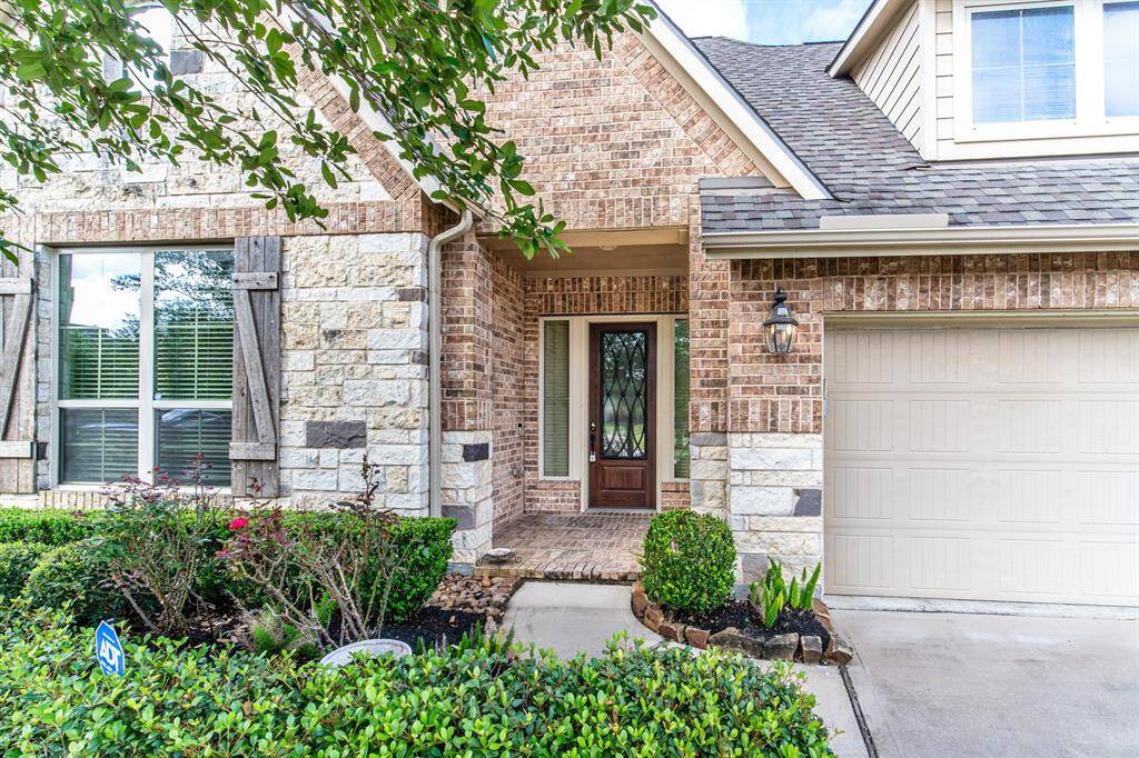 Stunning brick and stone home with a beautiful solid wood door adorned with metallic grill.