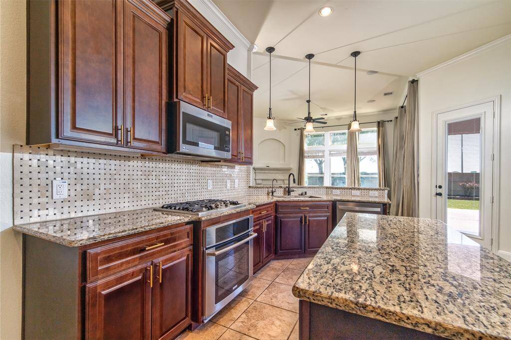 Kitchen with 42” cabinets, under-cabinet lighting, gas stove, granite countertops, refrigerator, and stainless steel appliances