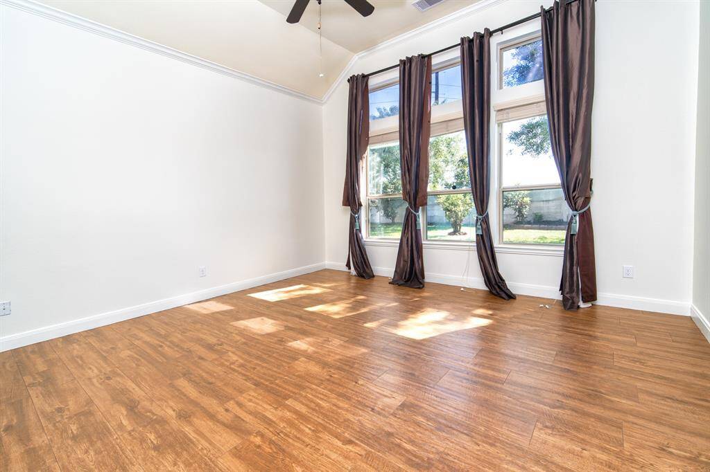 A blissful master bedroom that is already equipped with a TV for entertainment. Windows have floor-length drapes and blinds.