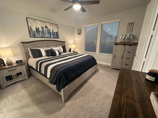 Primary bedroom with soft carpeting, and a ceiling fan for added comfort.