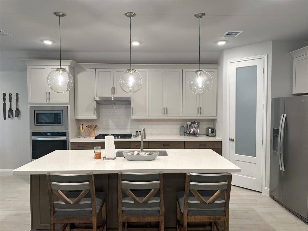 Designer lighting over the island enhances the kitchen's upscale feel.