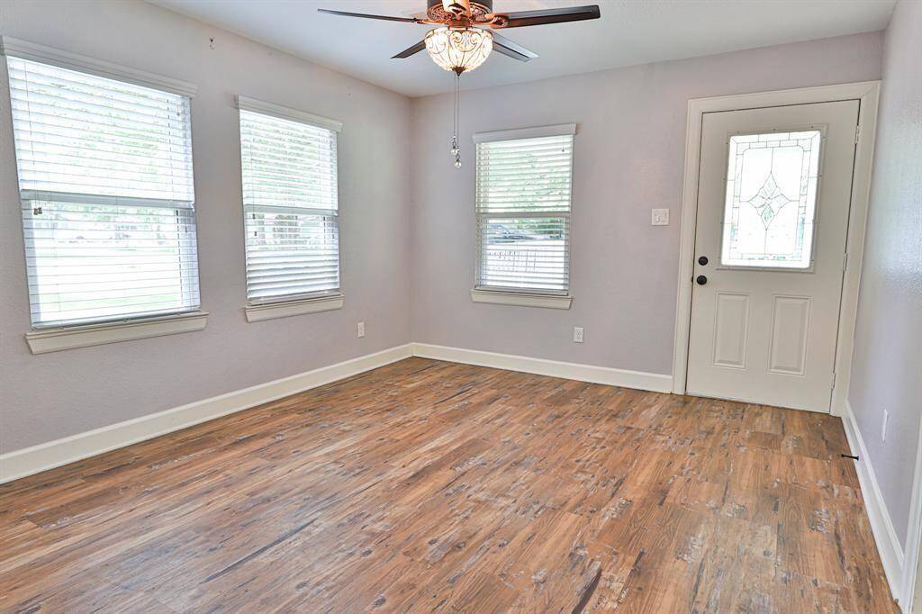 Wooden flooring enhances the space’s charm, complementing the natural light that streams in through the large windows with white blinds.
