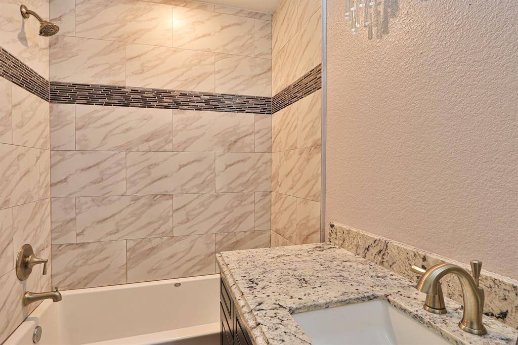 The spacious bathtub is framed by modern tiling, offering the perfect spot to unwind after a long day