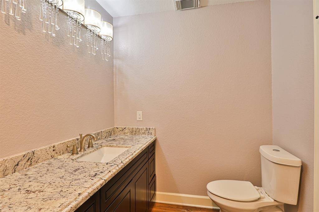A granite countertop vanity with rich wooden cabinetry provides ample storage while adding warmth to the space.