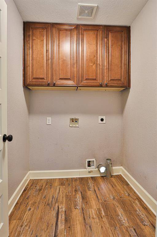 Designated area for a washer and dryer with wooden cabinetry.