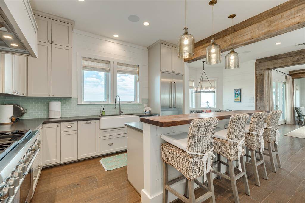 Backsplash is a seafoam green tile. Oversized porcelain farmhouse sink has a double and single basin