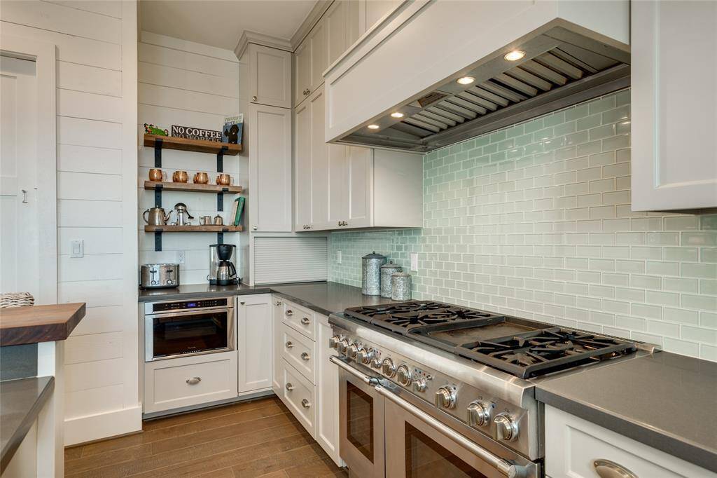 High-end Thermador appliance package includes an 8-burner gas stove with double ovens. There is also a coffee station and appliance garage at the end of the counter