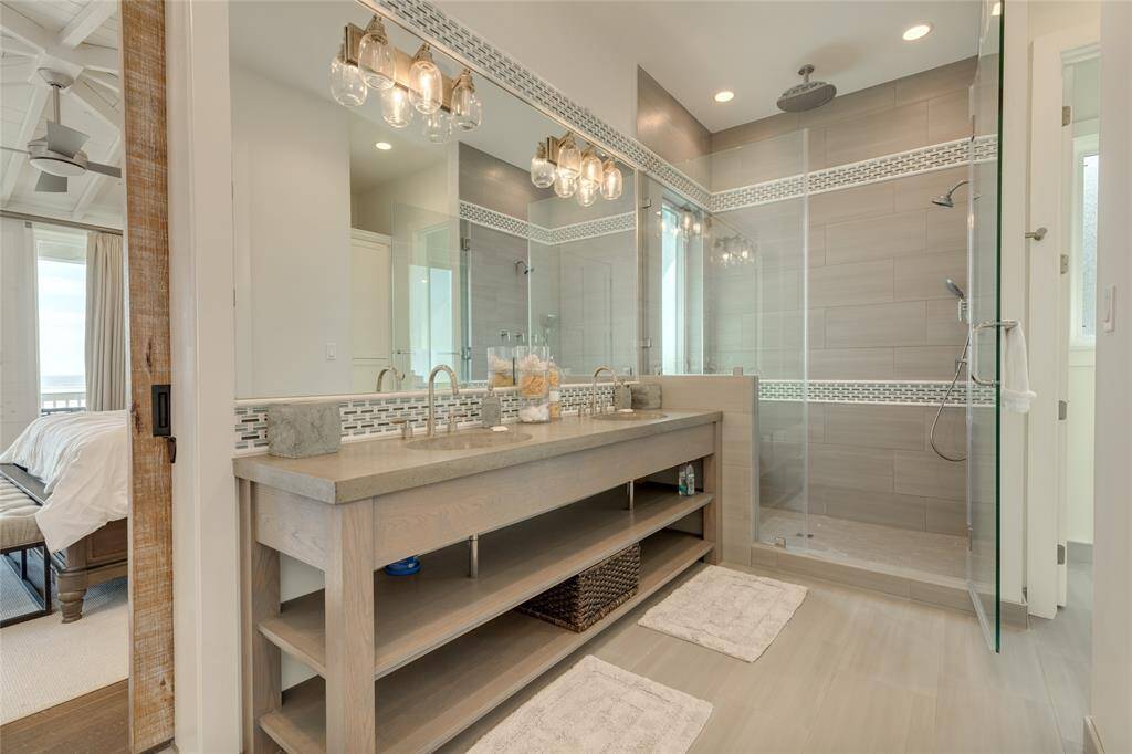 Double vanity in the Primary Bathroom is topped with a casted concrete countertop. Huge walk-in shower has multiple shower heads and a bench. There is also a walk-in closet with dresser and shelving