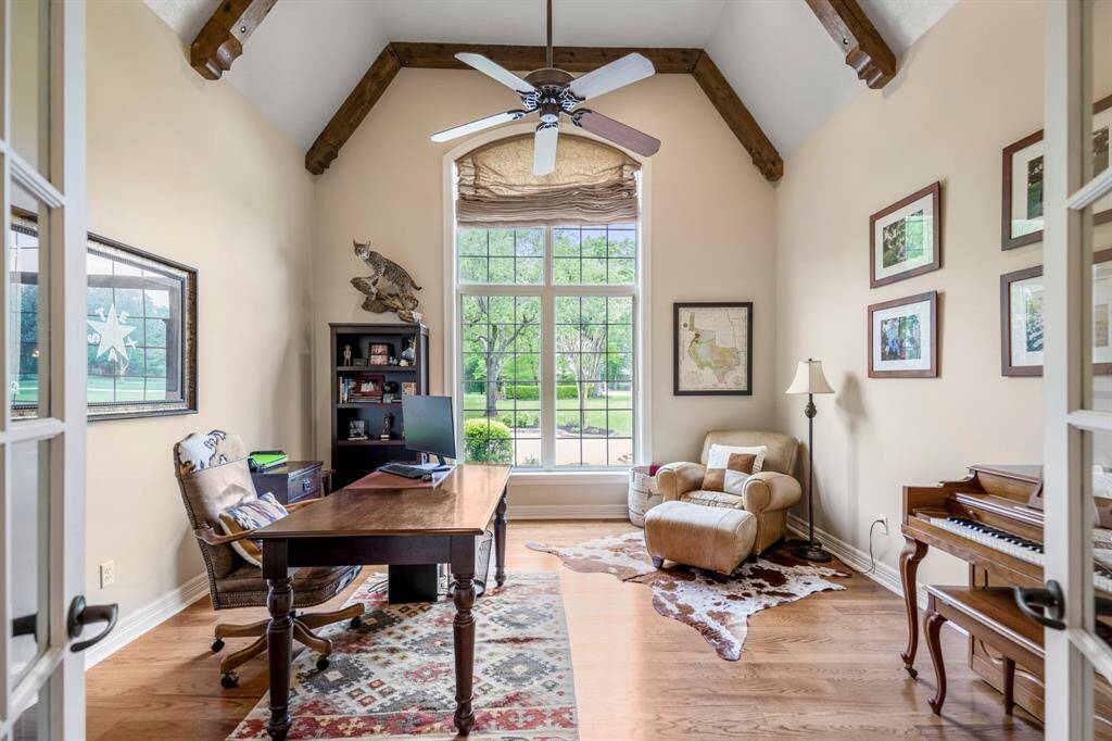 Bright home office with high vaulted ceilings and exposed wooden beams, large window providing tons of natural light