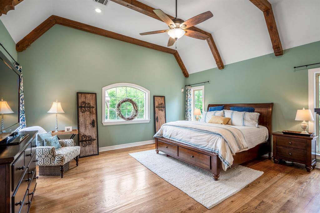 Luxurious first-floor primary bedroom featuring soaring vaulted ceilings with elegant beams.