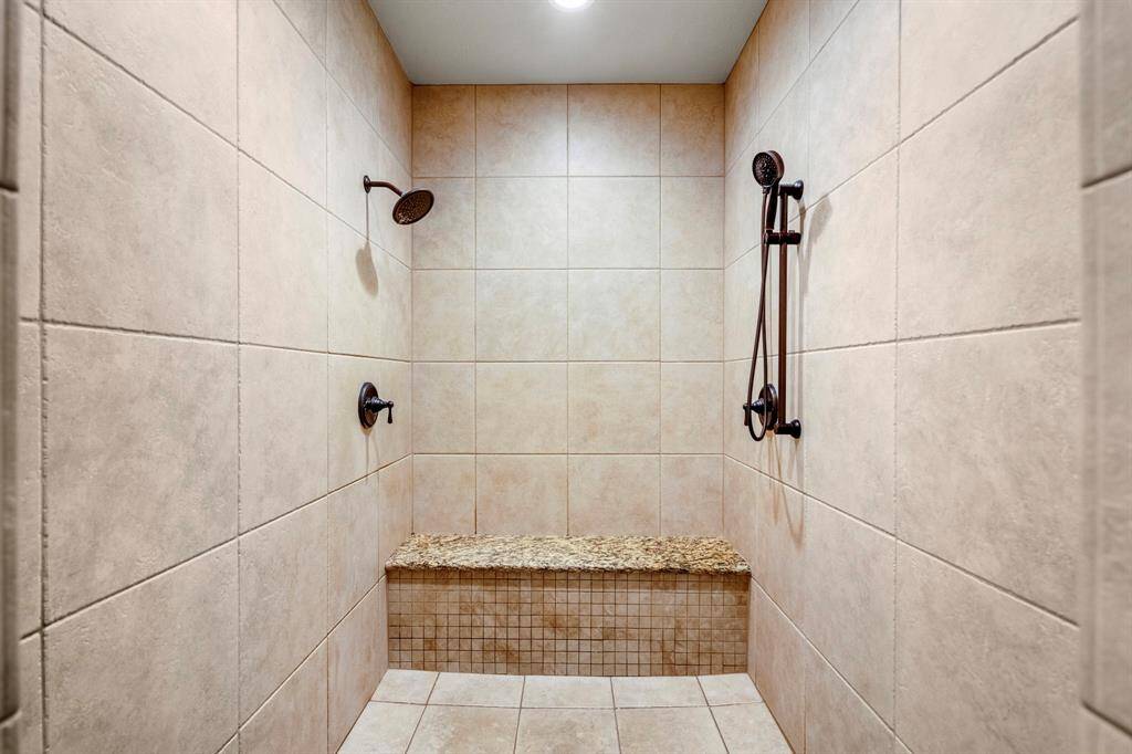 Spacious primary shower with elegant tile and dual shower heads for a lspa-like experience.
