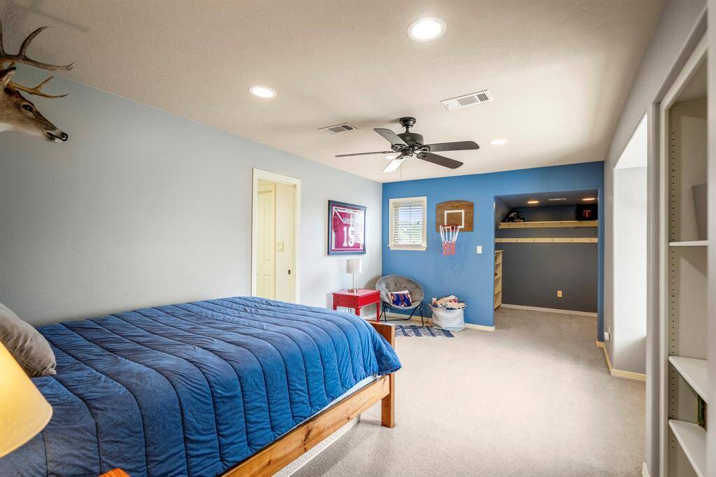 Cozy secondary bedroom featuring plush carpeting, elegant crown molding, ceiling fan, and a private en-suite bathroom.