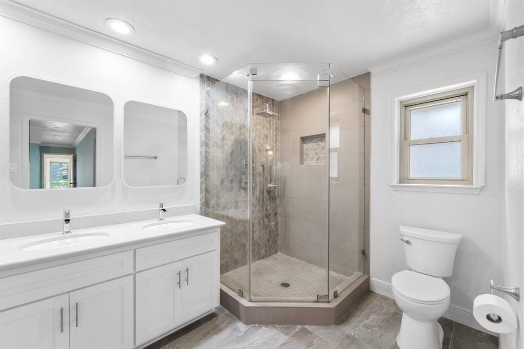 WOW! Spacious and beautifully appointed Primary Bathroom, featuring tile flooring, double sinks, mirrors, a shower, recessed lighting, and beautiful white cabinets with granite countertops.