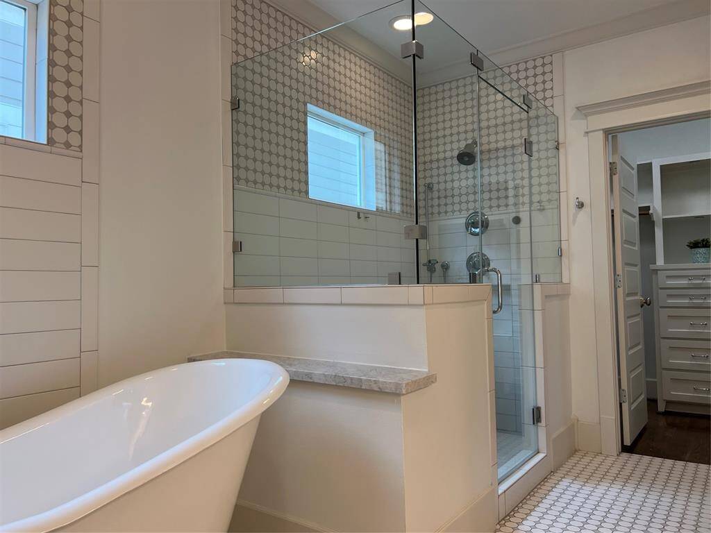 Walk in shower with glass walls and subway tile.