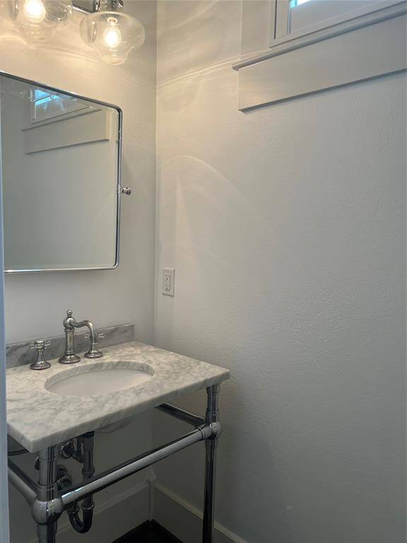 The powder room vanity has a marble counter top, elegant mirror and lights fixtures.
