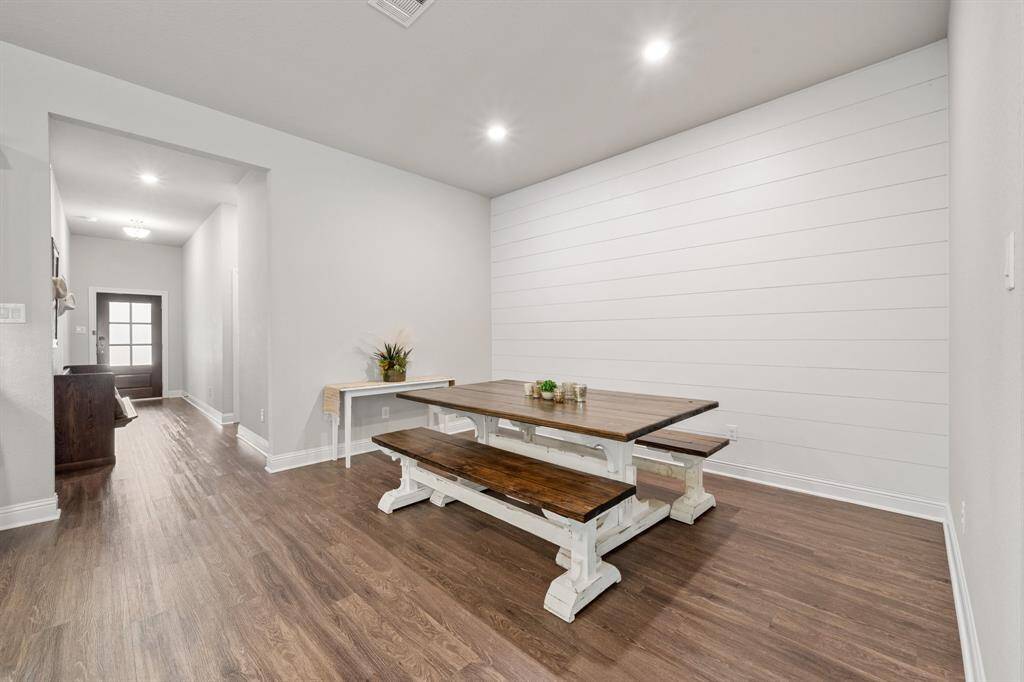 The dining room also matches the color of the door and furniture, creating a cohesive sense of familiarity. The space is further enhanced by beautiful white baseboards, which add a touch of elegance and contrast.