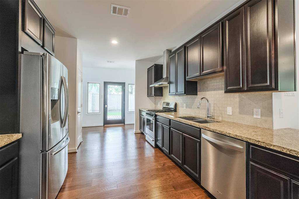 At the center of the home is the updated kitchen with granite countertops, stainless steel appliances and tall espresso stained cabinets as well as a pantry.