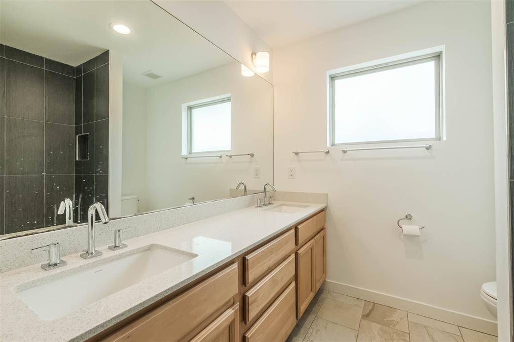 Hallway full bath shared by secondary bedrooms 1 and 2 has double sinks, natural light and a bathtub